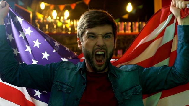 快乐的体育迷在酒吧里挥舞着美国国旗，庆祝最喜欢的球队胜利视频素材