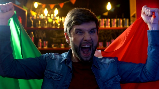 激动的男球迷挥舞着意大利国旗，庆祝国家运动队的胜利视频素材