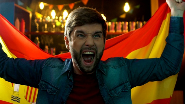 蓄着胡须的体育迷在酒吧里挥舞着西班牙国旗，庆祝西班牙国家队的胜利视频素材