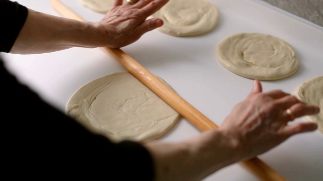多莉:年长的妇女在厨房柜台上用擀面杖擀面，为制作披萨或传统派做准备视频素材