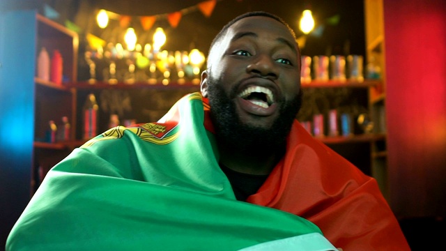 激动的黑球迷挥舞着葡萄牙国旗，庆祝国家运动队的胜利视频素材