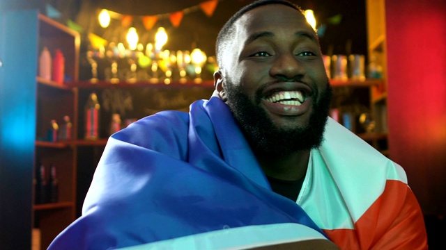 非裔美国球迷在酒吧挥舞法国国旗庆祝球队进球视频素材