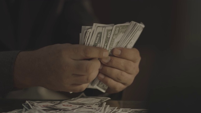 一个歹徒在桌子上数钱的特写镜头视频下载