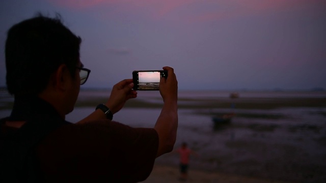 游客用智能手机自拍大海日落景观视频素材