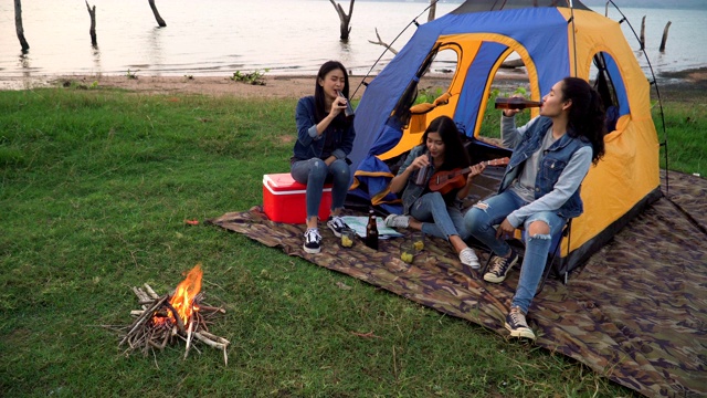 高角度视角:三个女人花周末时间露营在海边日落视频素材