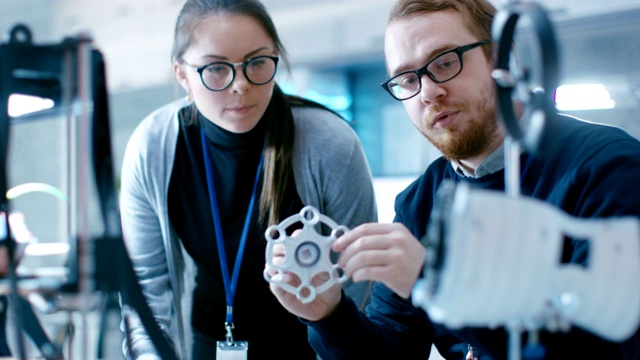 在一个现代实验室里有才华的年轻男女工程师使用3D打印机构建电子技术原型。视频素材
