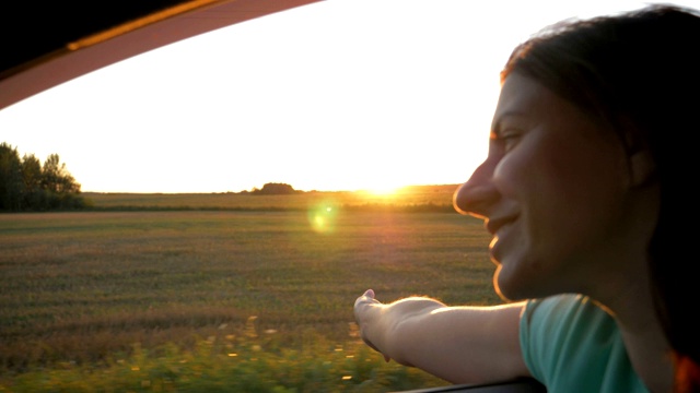 年轻漂亮的白人女人在车和手在空中玩日落射线视频素材