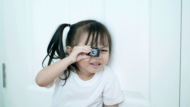 亚洲女婴的肖像，坐在地板上玩相机，情绪积极视频素材