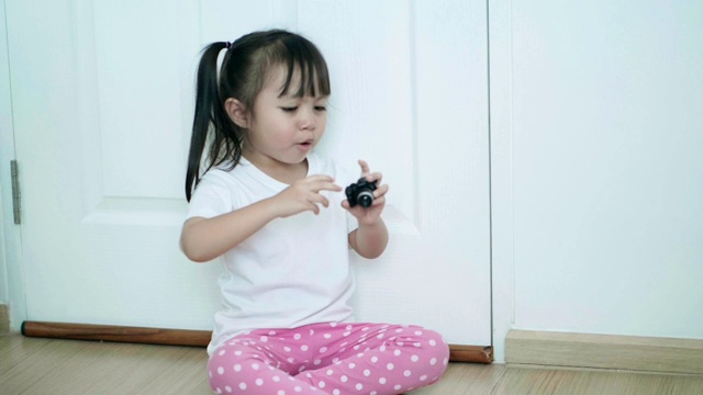 亚洲女婴的肖像，坐在地板上玩相机，情绪积极视频素材
