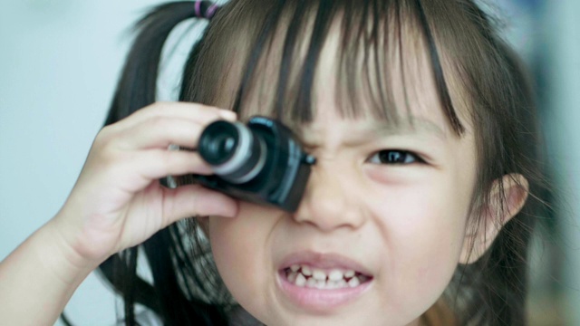 慢镜头泰国可爱的小女孩在镜子前玩相机玩具，同时笑着，情绪积极视频素材