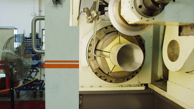 一位三十多岁的白人技术员准备一台在室内制造设施中旋转形成金属管的机器视频素材