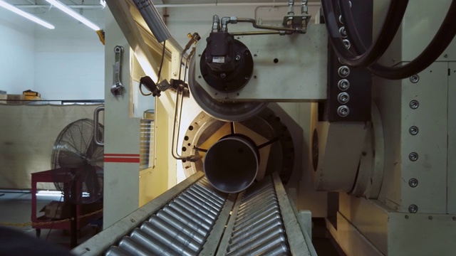 在室内制造设施中，一个三十多岁的白人技术员从旋转成形机的末端移除重力滚筒输送机视频素材
