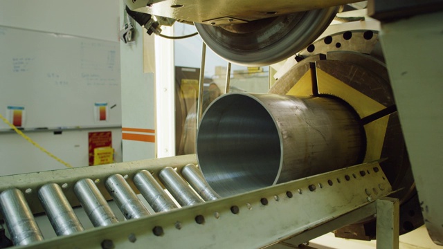 一名三十多岁的白人技术员在室内制造设施中将一根金属管推入机器中，以便为旋转成形做准备视频素材