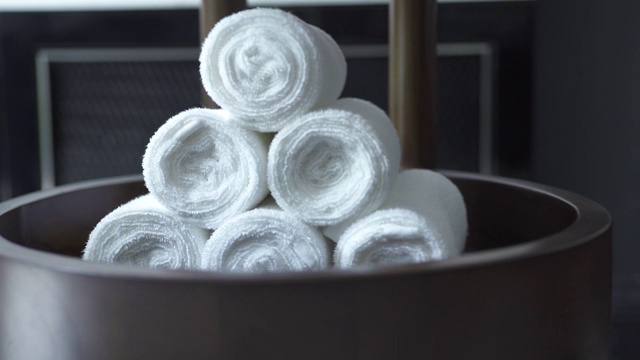 白色毛巾卷在现代水疗沙龙在黑暗的背景。黑色浴室里的白色浴巾。淋浴、水疗、桑拿、游泳池和浴缸配件视频素材