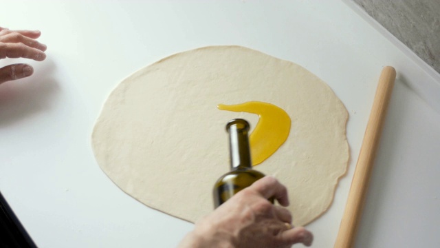 年长妇女在厨房柜台上用擀面杖擀面，为制作披萨或传统派做准备视频素材