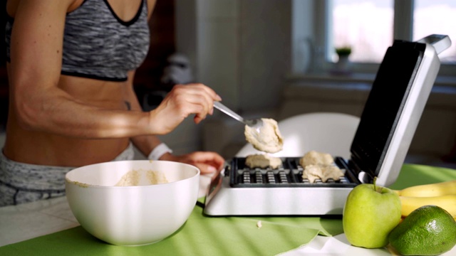一个运动的女人在厨房里做美味的比利时蓝莓华夫饼做早餐。视频下载