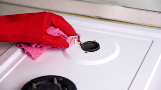 女人戴着红色橡胶手套，用刷子和海绵清洗脏煤气炉。视频素材