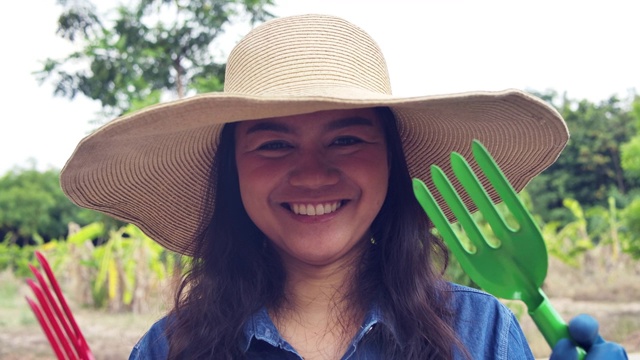 快乐的农妇微笑着展示她的园艺工具用具——锄头休闲活动视频下载