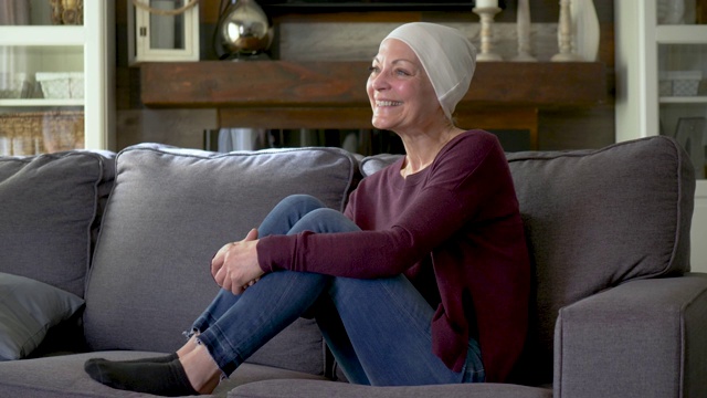 一位身患癌症的老年妇女正坐在沙发上。视频素材