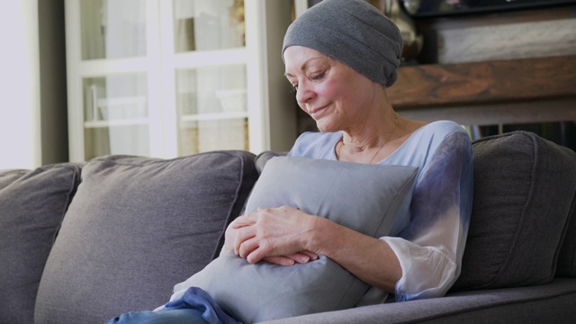 一位身患癌症的老年妇女正坐在沙发上。视频素材