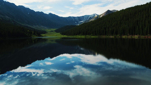 无人机拍摄的美丽的湖周围的树木和山脉视频素材