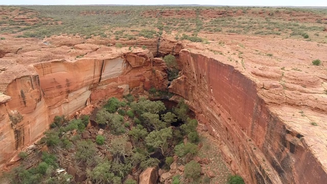 空中向前/向下:被峭壁包围的大洞，通向澳大利亚的乌卢鲁平原视频下载