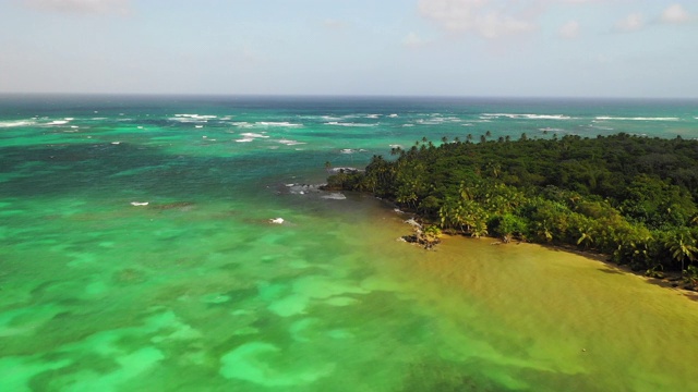 航拍右图:尼加拉瓜小玉米岛，生机勃勃的蓝色海洋旁的棕榈树森林视频下载