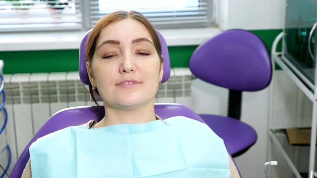 牙科医生在检查前给坐在牙科椅上的病人戴上眼镜。视频素材
