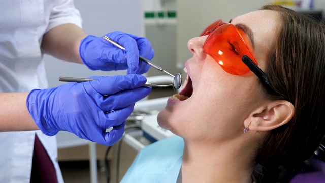 年轻女子在牙科诊所接受预防性检查。牙齿保健的概念。视频素材