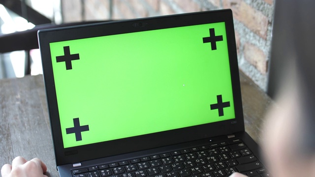 女人在绿色屏幕的笔记本电脑键盘上打字视频素材