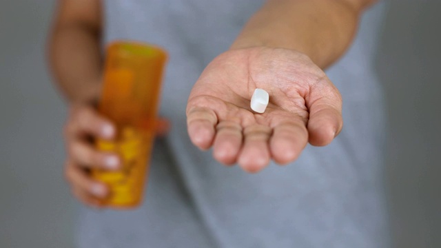 一名女子向镜头展示了一粒药丸，拿着药丸为自己服用。视频素材