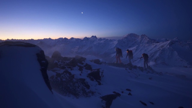 三个徒步旅行者在黎明时分爬上厄尔布鲁士山附近的一座山的慢动作镜头视频下载