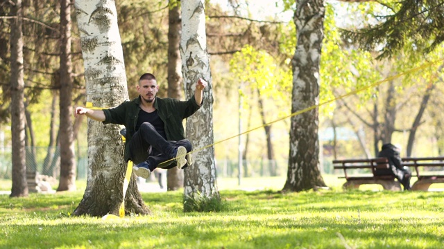 在公园里，一个年轻人在绳索上保持平衡视频下载