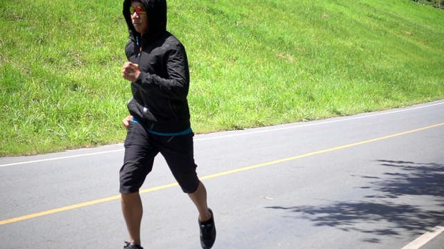 强壮的亚洲男性在户外的道路上奔跑。视频素材