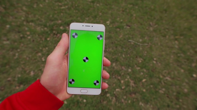 第一人称，智能手机空白绿色屏幕在一个男人的手走在草地上视频素材
