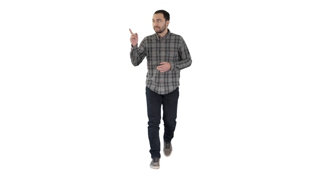穿着衬衫和牛仔裤的年轻自信的男人走向相机，指着白色背景的两边视频素材