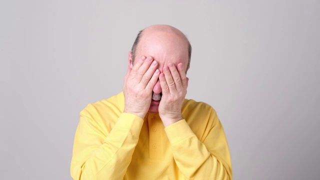 穿黄衬衫的人用手蒙住脸。视频素材