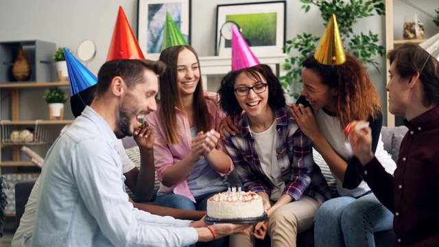 年轻的女士在生日聚会上和朋友吹蜡烛许愿视频素材