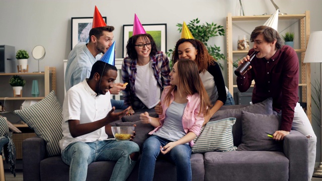 戴着派对帽的朋友们笑着祝贺女孩的生日，喂她薯片视频下载