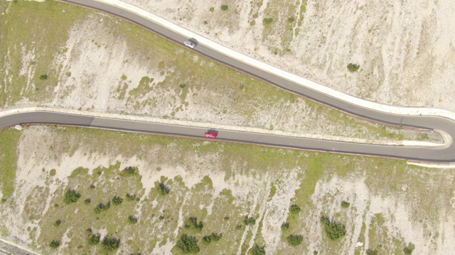 无人机:飞过两辆红色汽车在意大利Dolomites弯曲的道路上相遇视频下载