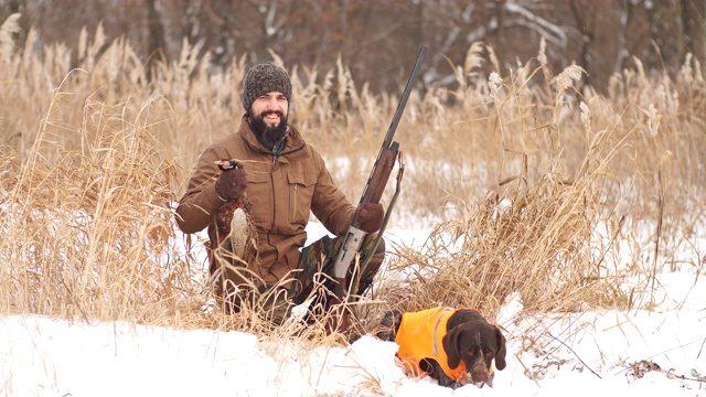 一个寒冷的冬天，疲惫的猎人和他的狗正在休息视频下载