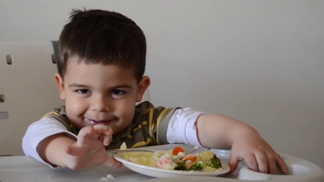脾气暴躁的两岁小男孩玩食物，拒绝吃东西视频素材