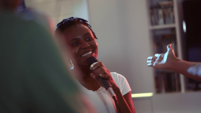 美丽的非洲女人拿着麦克风唱歌。近距离视频下载