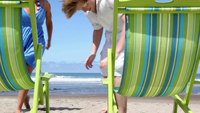 一对情侣在沙滩上跑到椅子上视频下载