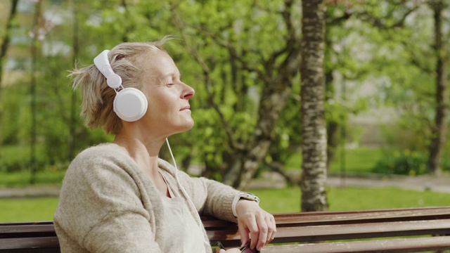 女人在公园里放松和听音乐视频下载