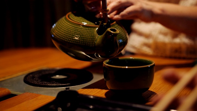在一家泛亚洲餐厅里，一位女士在往茶杯里倒茶。视频下载