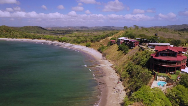 空中右转:尼加拉瓜，El Gigante，充满活力的海洋海岸边的草地上的大红房子视频素材