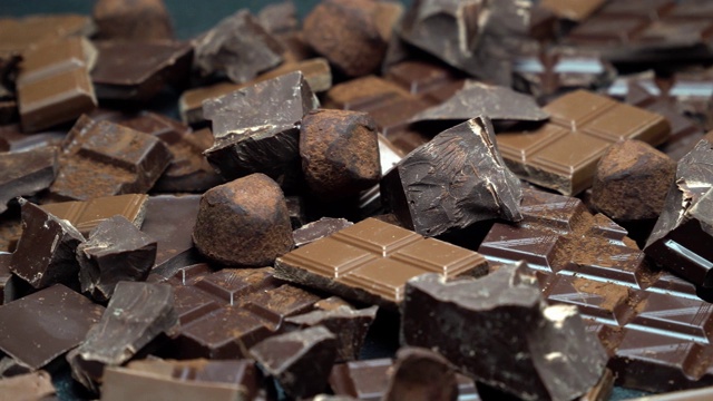 深色或牛奶有机巧克力块，可可粉和松露糖果在深色混凝土背景视频素材