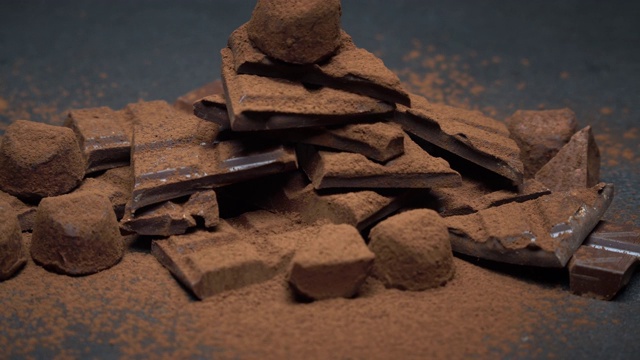 深色或牛奶有机巧克力块，可可粉和松露糖果在深色混凝土背景视频素材