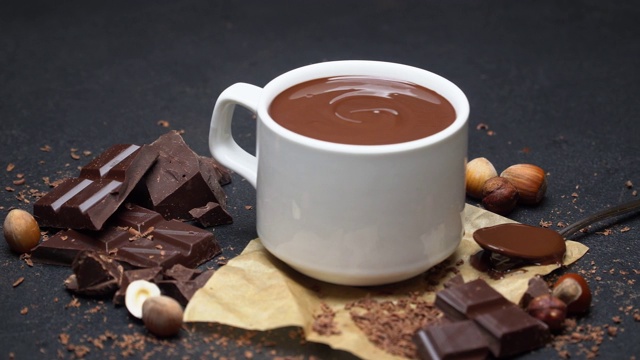 一杯热巧克力和巧克力块在黑色的混凝土背景视频下载